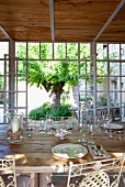 Set dining table in front of open terrace doors and lattice windows of Mediterranean extension