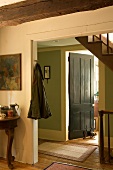 Schlichter Wohnraum im Bauernhaus mit offenem Durchgang und Blick in Vorraum mit Treppe