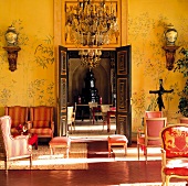 Red Rococo seating against gold tapestries with Chinese motifs on walls of grand hotel salon