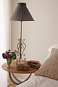 Bedside lamp with grey lampshade on wooden bedside table next to bed