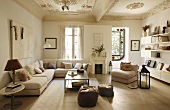 Generous corner sofa and floating shelving in simple, modern living room in period apartment below immaculate stucco ceiling