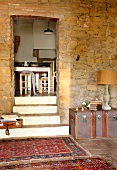 Rugs on floor of foyer with stone walls and steps leading to dining room doorway