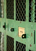 Row of locks on old wire lockers painted industrial green