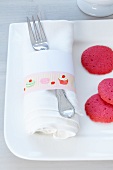 Masking Tape mit Süßigkeiten-Illlustration auf Serviettenring, Teller mit pinkfarbenen Keksen