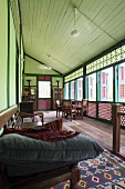 Veranda of traditional Oriental wooden house with latticed wood balustrade and cushions on dark wood bench