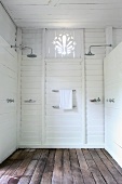 Twin shower heads in simple shower area with white wood panelling and wooden floor