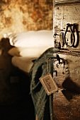 View of bed through open rustic wooden door with vintage door handle and label hanging from key
