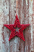 Star made of red twigs against weathered wooden wall
