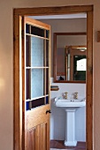 View through open door of pedestal washbasin and mirror