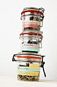 Three flip top jars filled with various types of tea and labelled with masking tape