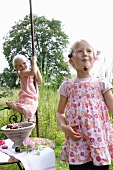 Zwei blonde Mädchen essen Kirschen im Garten