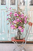 Bouquet of magnolia in glass vase on wooden chair