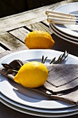 Zitronen und Tellerstapel auf rustikalem Tisch