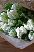 Bouquet of tulips wrapped in paper lying on surface