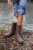 Girl taking off rain boots by pond