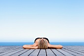 Woman sunbathing on wooden pier