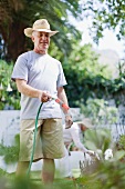 Older man watering plants in garden