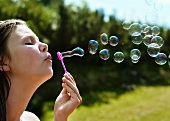Girl blowing soap bubbles in meadow