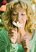 Senior woman smelling daisy