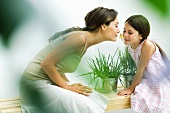 Woman and daughter smelling flower sprig together