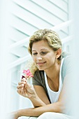 Woman looking down at flower in hand, smiling