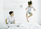 Boys on bed, one in mid air