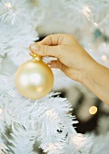 Child putting ornament on christmas tree