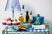 Desserts auf der Schale vor Tischlampe mit blauem Schirm und verschiedene Küchenutensilien