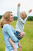Mother holding cheerful son in meadow