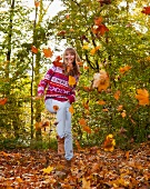 Frau hüpft im Herbstlaub