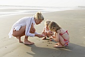 Mutter und Kinder spielen am Strand