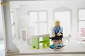 Doll sitting in chair in doll house