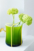 Green vase with rubber band holding flowers in place
