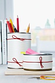 Pencil holders made from tin cans decorated with paper and rubber bands