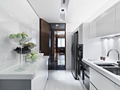 Sideboard mit Obstschalen in weisser Designerküche und Blick durch offene Tür in Wohnraum