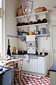 Schlichte Küchenzeile in ländlicher Wohnküche mit rot-weißem Schachbrettmusterboden