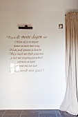 Message written on wall next to floor-length curtain in modern foyer