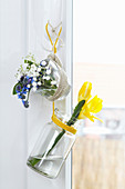 Suspended jar and glass espresso cup holding freesias and forget-me-nots