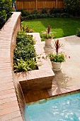 Raised bed with brick wall and terrace next to pool in garden