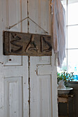 Sign made of branches with the inscription "BAD" on a white wooden door