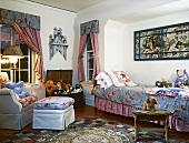 Child's bedroom with bedspread and curtains in matching fabric and many soft toys on the bed and in a wooden trunk