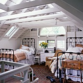 Two black, iron beds and a semi-circular window in white, attic bedroom with wooden walls