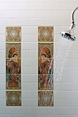 Chrome shower head with running water; Art Nouveau wall tiles in background