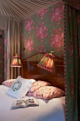 Himmelbett mit schweren Vorhängen und mit Wandtapete, Nachttischlampen und Kissen im floralen Muster