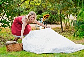 Blonde Frau breitet eine Picknickdecke aus