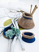 Small, two-tone, crocheted bags for nick-nacks arranged with white-painted twigs and succulent plants