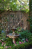 Weathered stone fountain in front of wooden garden fence