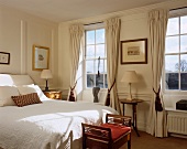 Traditionelles Schlafzimmer mit bodenlangen Vorhängen an Sprossenfenstern
