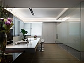 Moderne, minimalistische Küche mit langer Küchentheke und glänzender Glasfront