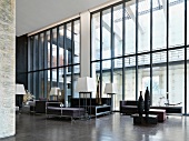 Imposante Fensterfront in einer Lounge mit modernen Sitzmöbeln und Stehlampen mit quadratischem Lampenschirm